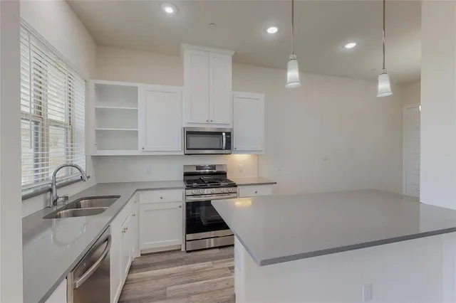 a kitchen with stainless steel appliances a sink stove and white cabinets