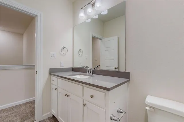a bathroom with a granite countertop sink and a toilet