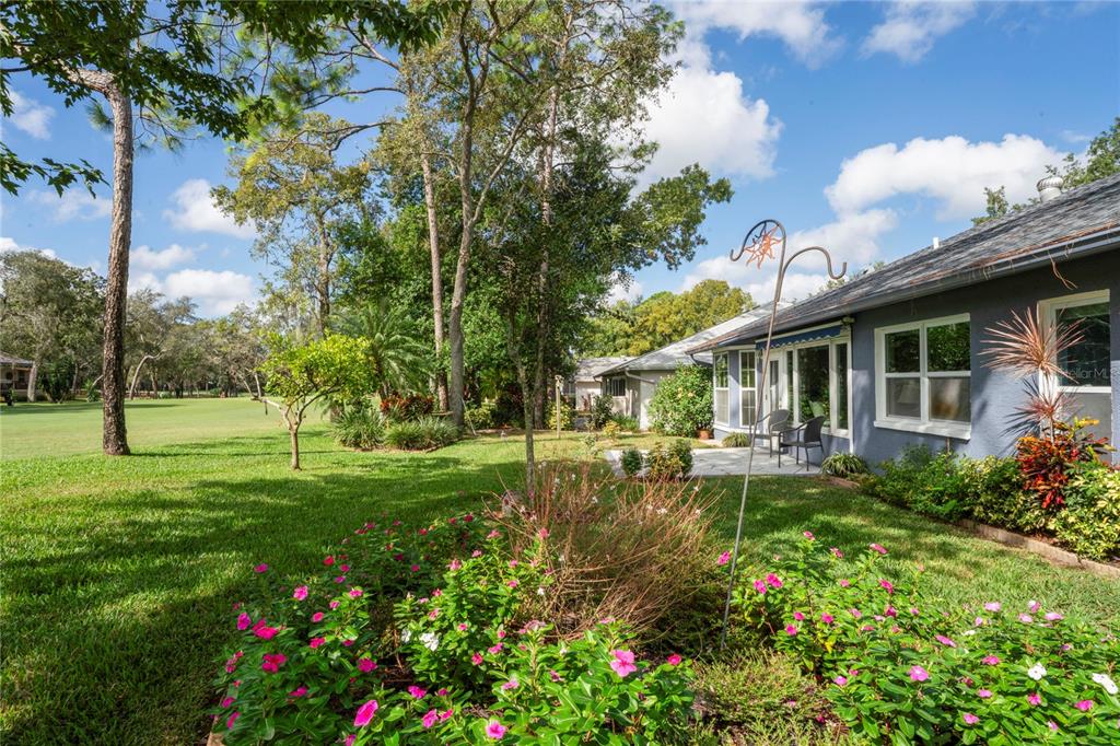 7112 Green Abbey Way Spring Hill, FL 34606 - Photo 39 of 66 a backyard of a house with table and chairs plants and large tree