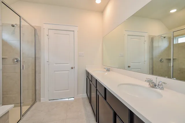 a bathroom with a double vanity sink mirror and shower