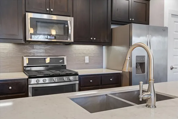 a kitchen with stainless steel appliances granite countertop a sink a window and wooden floor