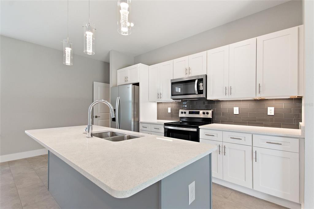 24399 Southwest Kingsway Circle Punta Gorda, FL 33983 - Photo 13 of 38 a kitchen with stainless steel appliances a sink a stove a microwave a center island and cabinets