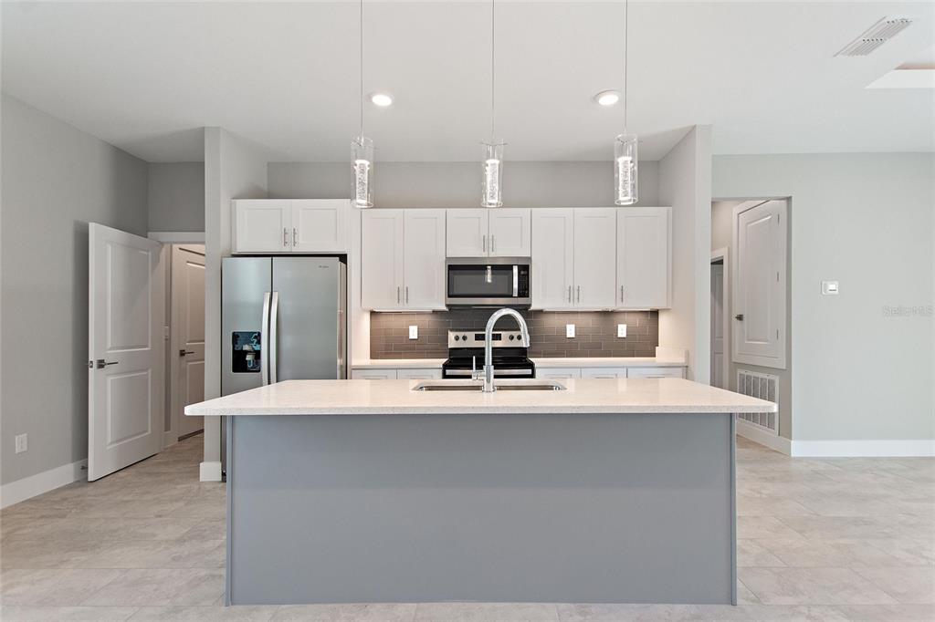 24399 Southwest Kingsway Circle Punta Gorda, FL 33983 - Photo 14 of 38 a large kitchen with stainless steel appliances a refrigerator and a stove top oven