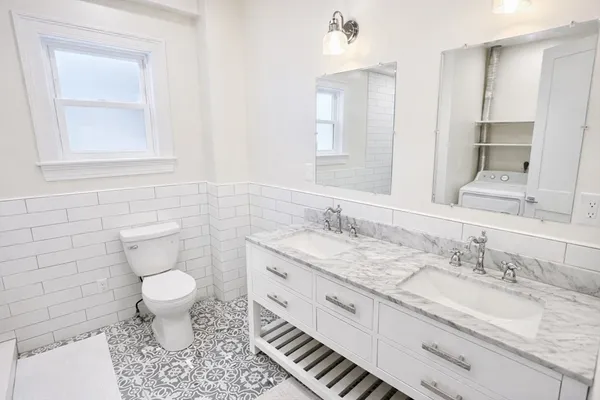a bathroom with a granite countertop toilet sink and mirror