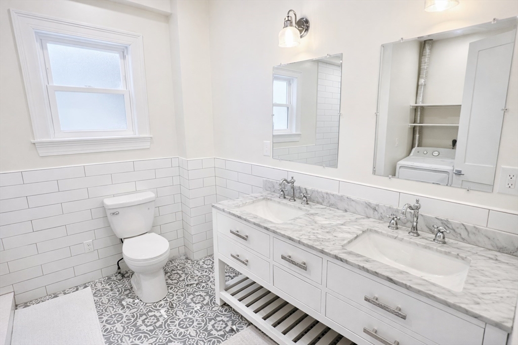 35 Foster Street, Unit 1 Boston, MA 02135 - Photo 15 of 21 a bathroom with a granite countertop toilet sink and mirror