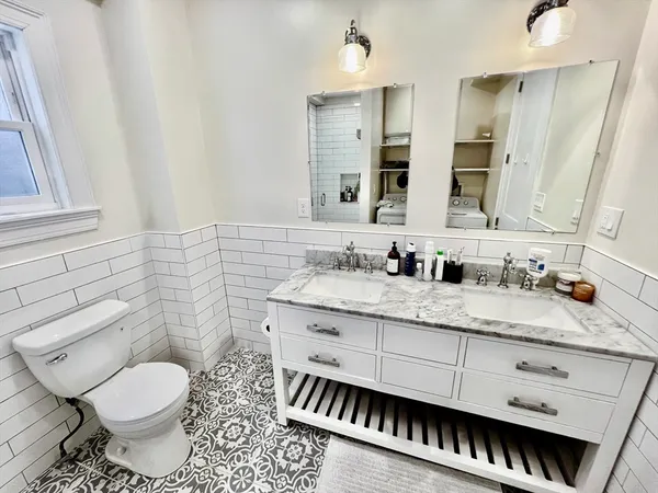 a bathroom with a granite countertop toilet sink and mirror