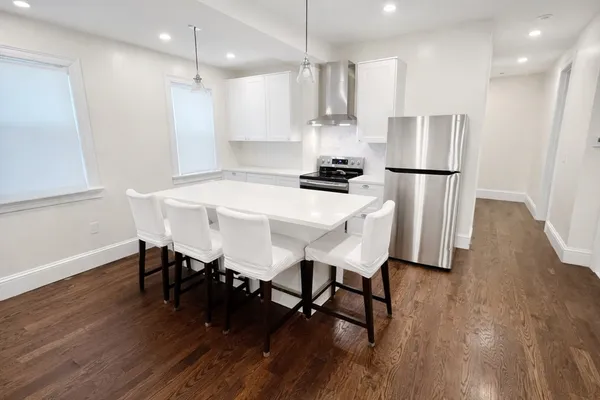 a kitchen with stainless steel appliances a table chairs wooden floors and view living room