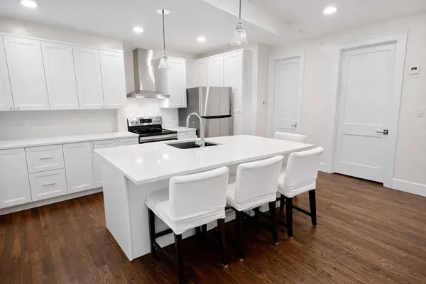 a kitchen with stainless steel appliances a white table chairs and a refrigerator