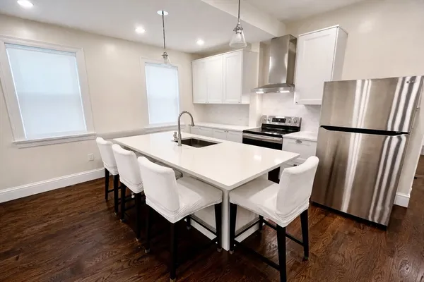 a kitchen with stainless steel appliances a dining table chairs wooden floor and a refrigerator