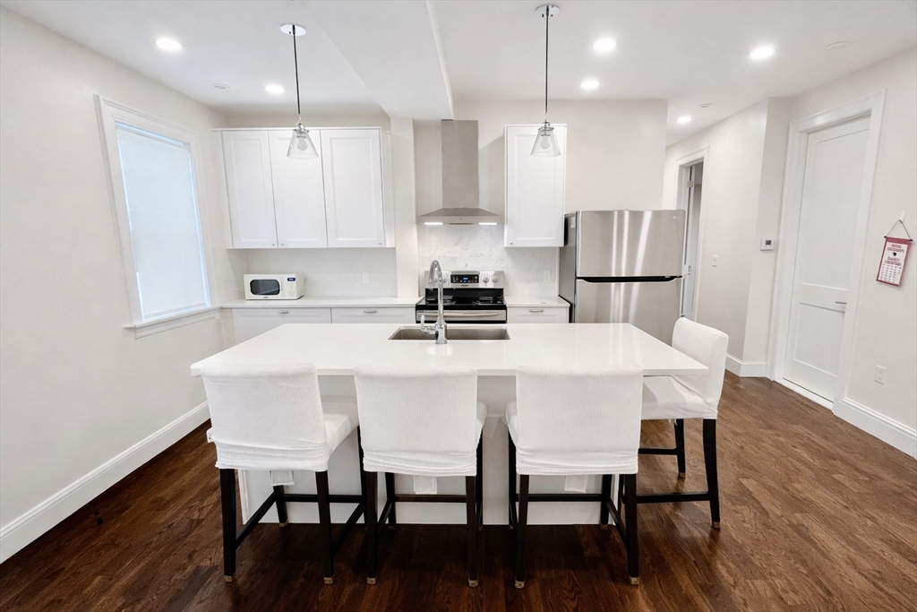 35 Foster Street, Unit 1 Boston, MA 02135 - Photo 6 of 21 a kitchen with stainless steel appliances a dining table chairs refrigerator sink and microwave