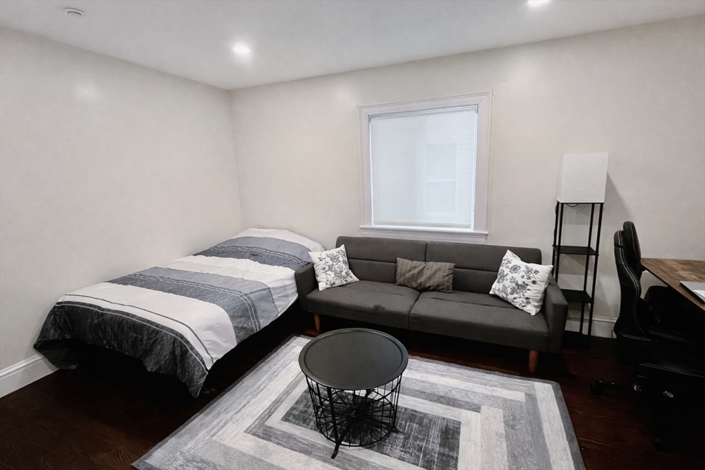 35 Foster Street, Unit 1 Boston, MA 02135 - Photo 9 of 21 a spacious bedroom with a bed a couch and a large mirror