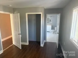 a view of a hallway with wooden floor and a bathroom