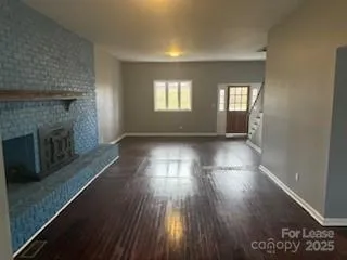 an empty room with wooden floor and fireplace