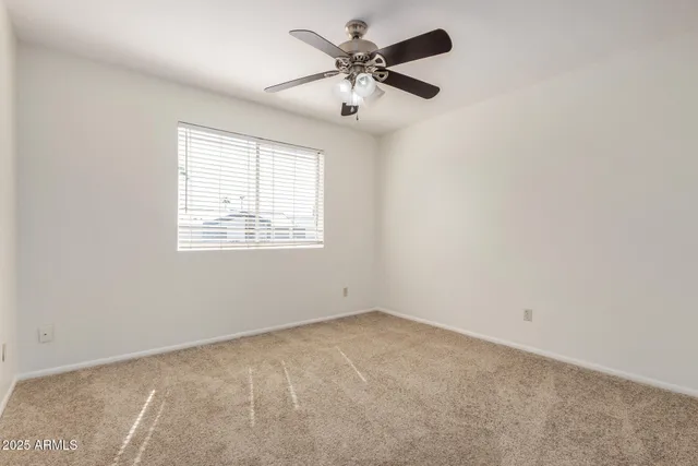 an empty room with a ceiling fan and a window