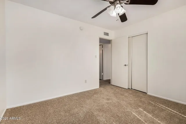 an empty room with a window and a fan