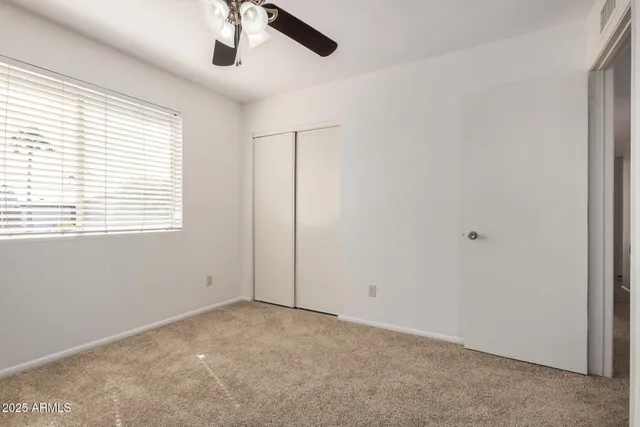 an empty room with a window and a fan