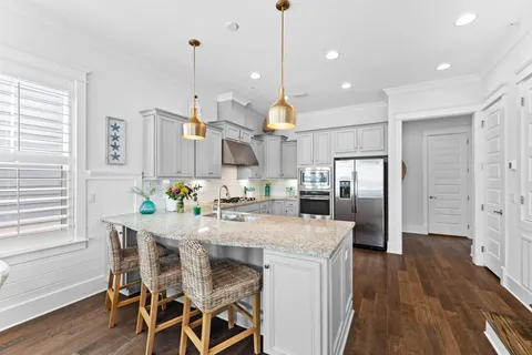 a kitchen with stainless steel appliances kitchen island granite countertop a table chairs and a refrigerator