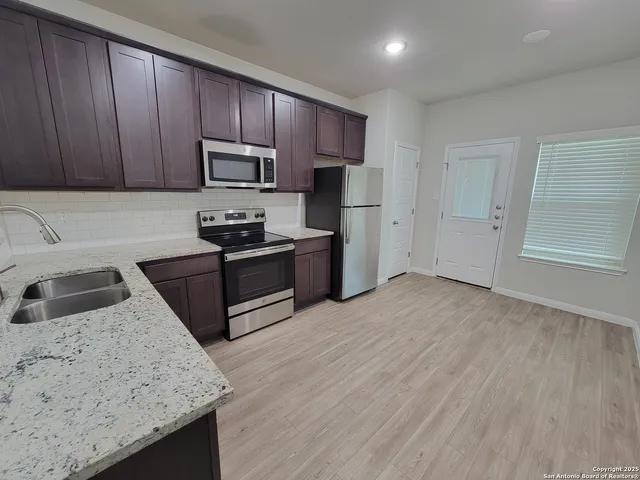 a kitchen with granite countertop wooden cabinets a sink and stainless steel appliances