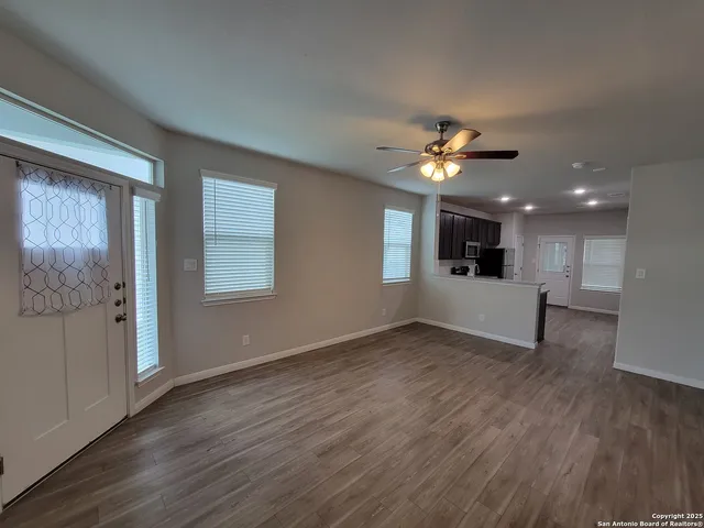 a view of an empty room with a window and wooden floor