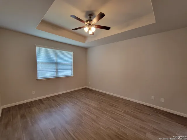 an empty room with wooden floor and ceiling fan