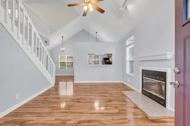 a view of an empty room with wooden floor fireplace and a window