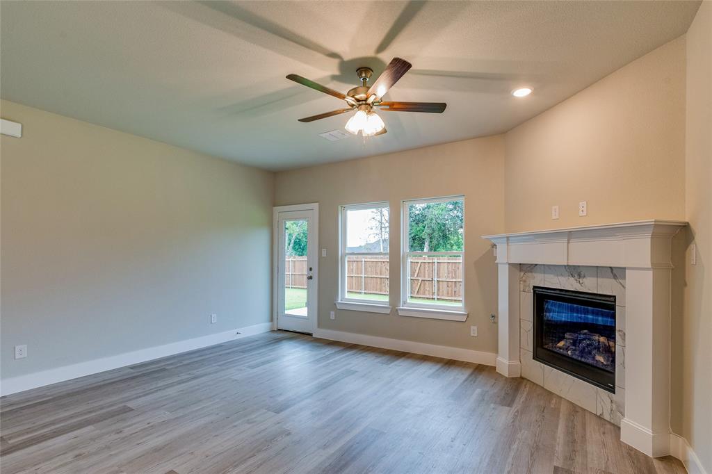 602 Kyle Drive Tioga, TX 76271 - Photo 13 of 29 an empty room with wooden floor a ceiling fan a fireplace and windows