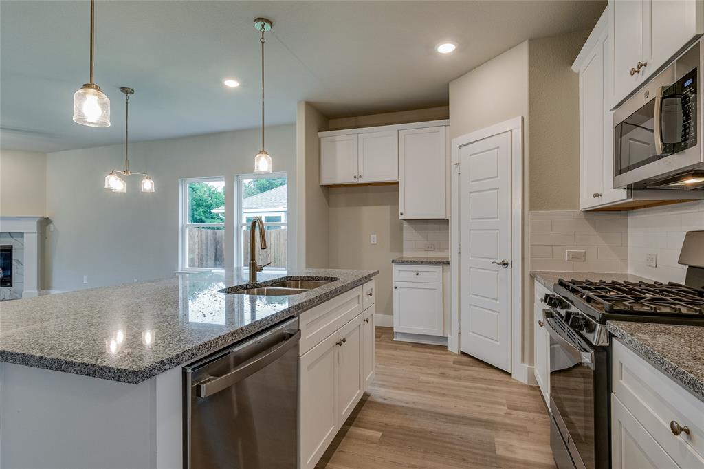 602 Kyle Drive Tioga, TX 76271 - Photo 7 of 29 a kitchen with stainless steel appliances granite countertop a sink a stove and a wooden floors
