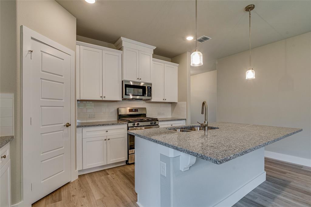 602 Kyle Drive Tioga, TX 76271 - Photo 10 of 29 a kitchen with kitchen island granite countertop a sink cabinets and wooden floor