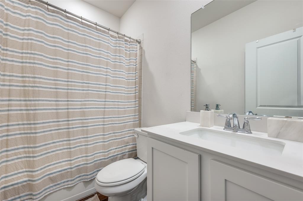 11105 Autry Ridge Lane Aubrey, TX 76227 - Photo 12 of 27 a bathroom with a granite countertop toilet a sink a mirror and a shower curtain