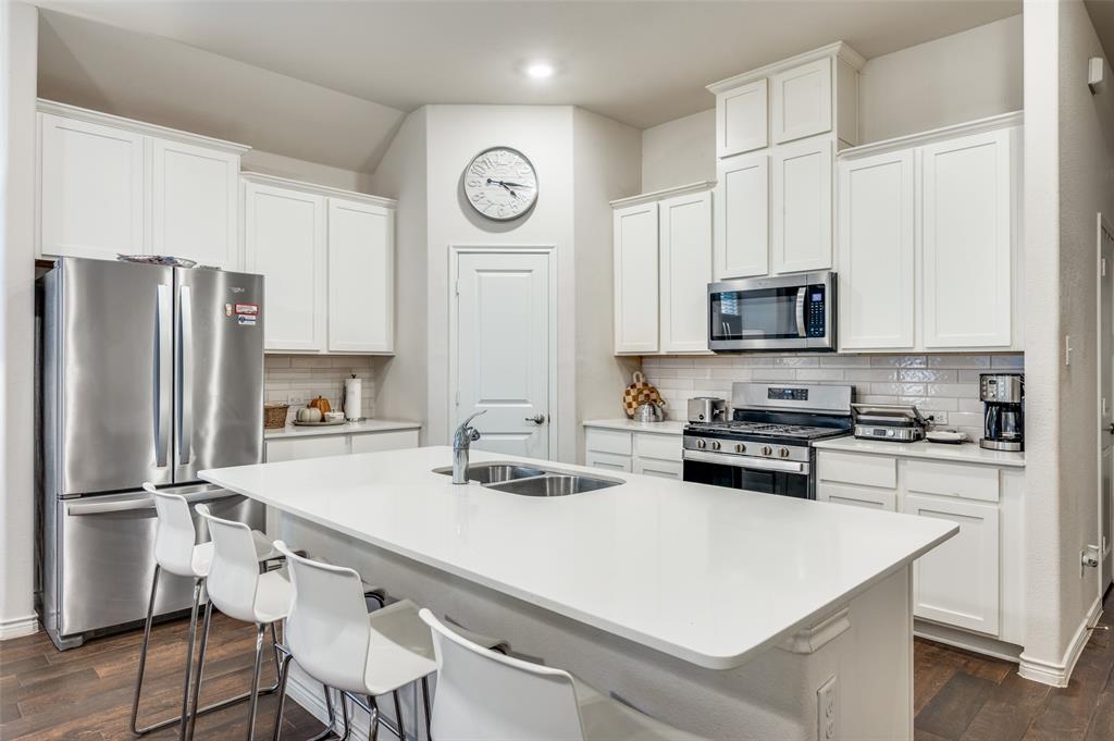 11105 Autry Ridge Lane Aubrey, TX 76227 - Photo 4 of 27 a kitchen with a refrigerator a stove a sink and white cabinets