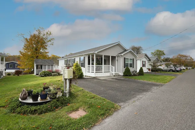 a front view of a house with a garden and trees