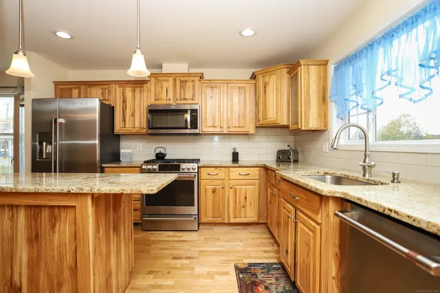 a kitchen with kitchen island granite countertop a sink stainless steel appliances and cabinets