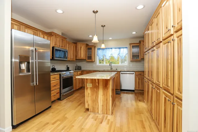 a kitchen with kitchen island a counter top space a sink stainless steel appliances and cabinets