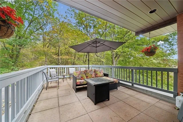 a view of a patio with a table and chairs under an umbrella with a small garden