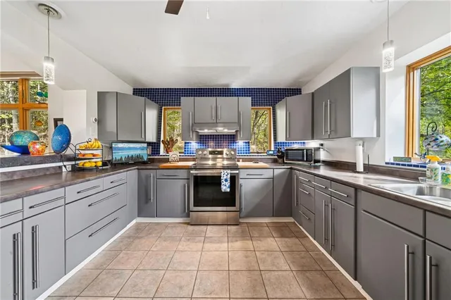 a kitchen with stainless steel appliances granite countertop a stove a sink dishwasher and a microwave oven with white cabinets