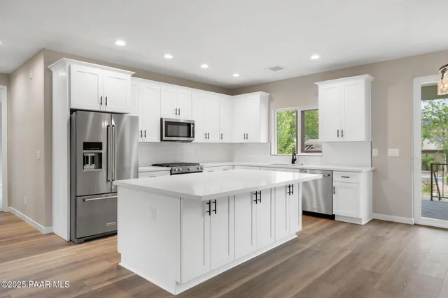 a kitchen with a refrigerator a sink dishwasher and a stove with wooden floor