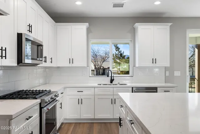 a kitchen with white cabinets and appliances