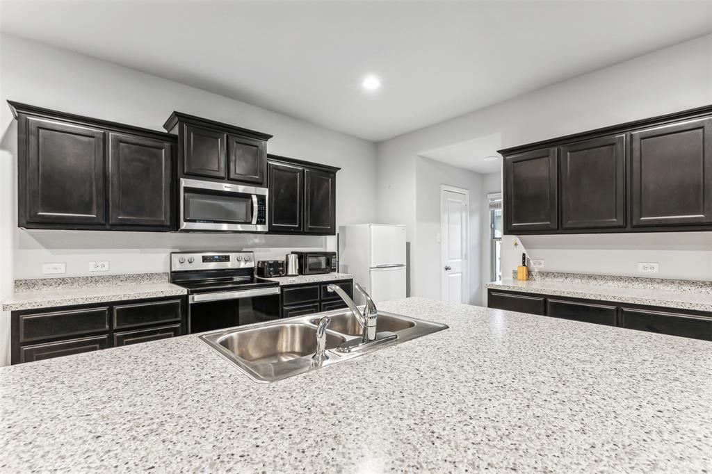 714 Wolf Creek Cleburne, TX 76033 - Photo 15 of 40 a kitchen with granite countertop a stove a microwave and refrigerator