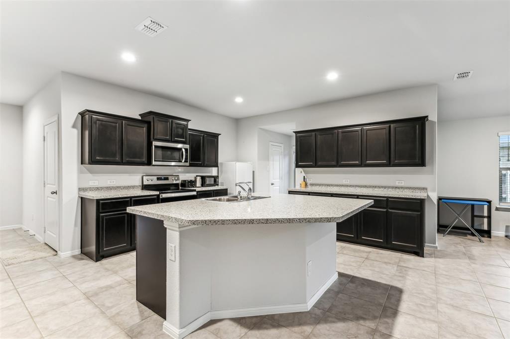 714 Wolf Creek Cleburne, TX 76033 - Photo 18 of 40 a kitchen with stainless steel appliances a stove sink microwave and cabinets