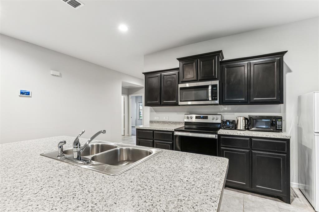 714 Wolf Creek Cleburne, TX 76033 - Photo 10 of 40 a kitchen with stainless steel appliances granite countertop a sink stove and refrigerator