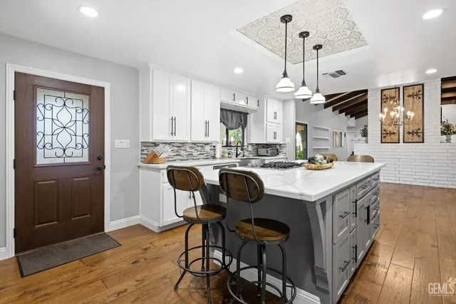 a kitchen with kitchen island granite countertop a sink a counter space appliances and cabinets