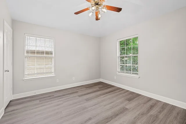 a view of an empty room with wooden floor and a window