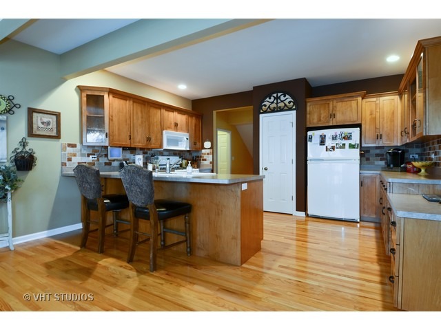 756 Ridge Drive Elburn, IL 60119 - Photo 3 of 18 a kitchen with stainless steel appliances kitchen island granite countertop a refrigerator a stove a microwave oven with a dining table and chairs