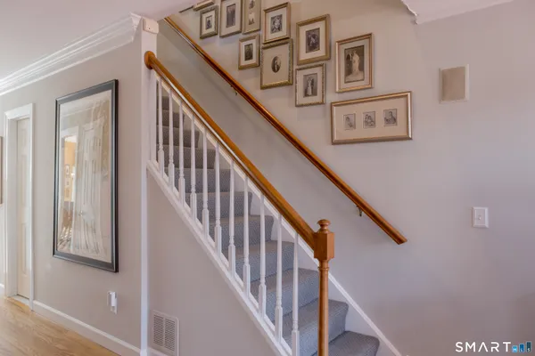 a view of staircase with lots of frames on wall and wooden floor