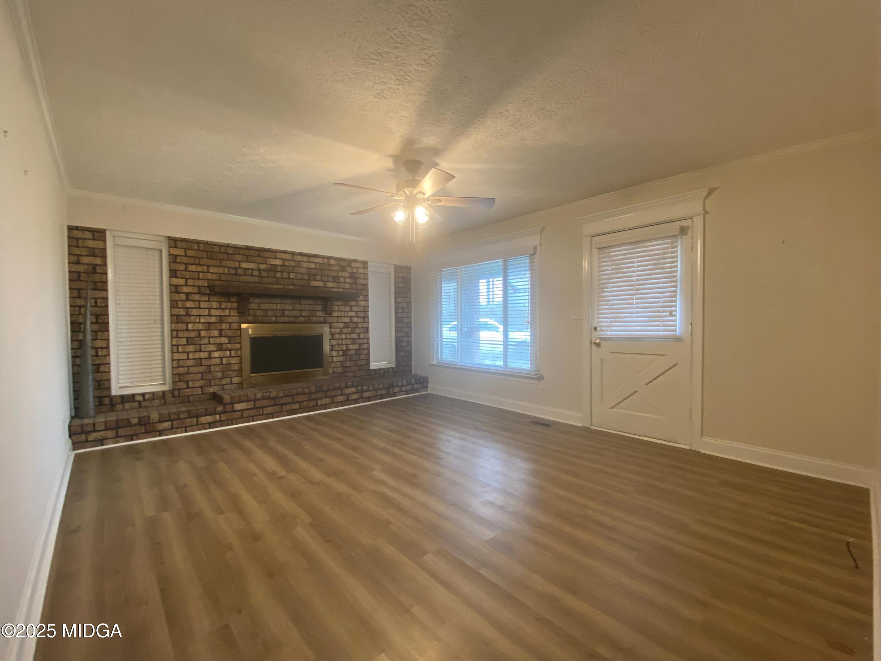 727 Walker Road Byron, GA 31008 - Photo 3 of 23 an empty room with wooden floor fireplace and windows