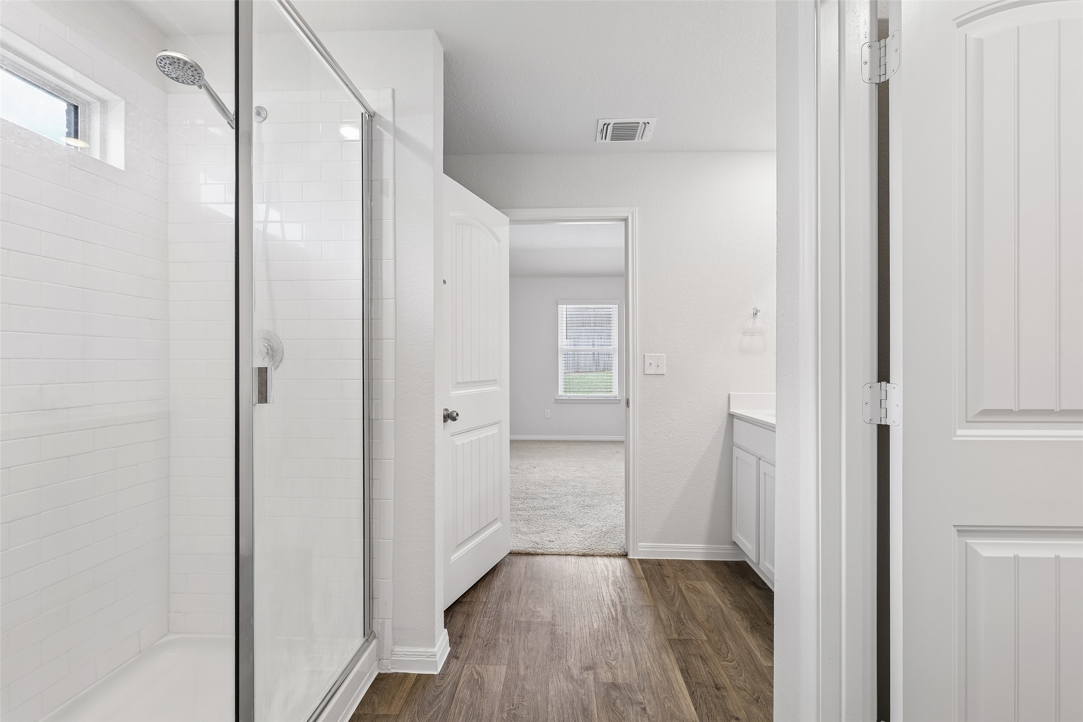 19805 Abigail Fillmore Road Manor, TX 78653 - Photo 19 of 40 Gleaming wood-look flooring connects this bright bathroom's sleek glass-enclosed shower and vanity area to the adjoining bedroom.