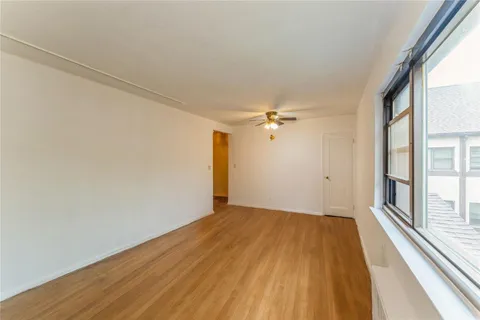 a view of empty room with wooden floor and fan