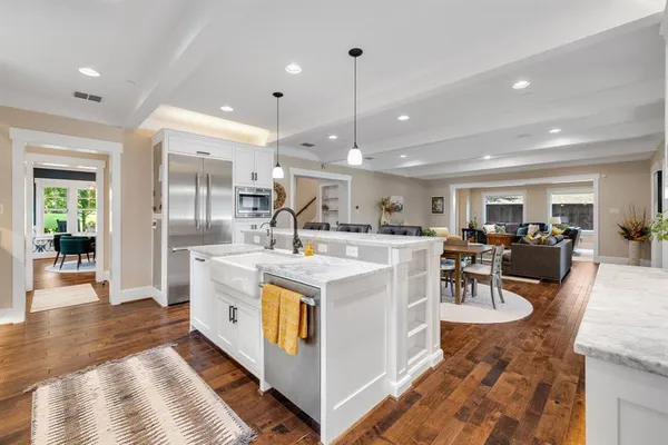 a view of a kitchen with kitchen island stainless steel appliances refrigerator stove dining table and chairs