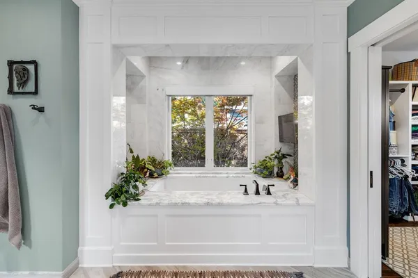 a white bath tub sitting in a bathroom next to a window
