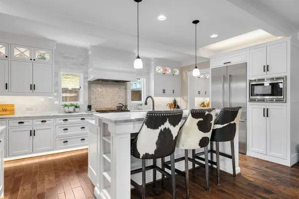 a kitchen with stainless steel appliances kitchen island granite countertop a table chairs microwave and sink